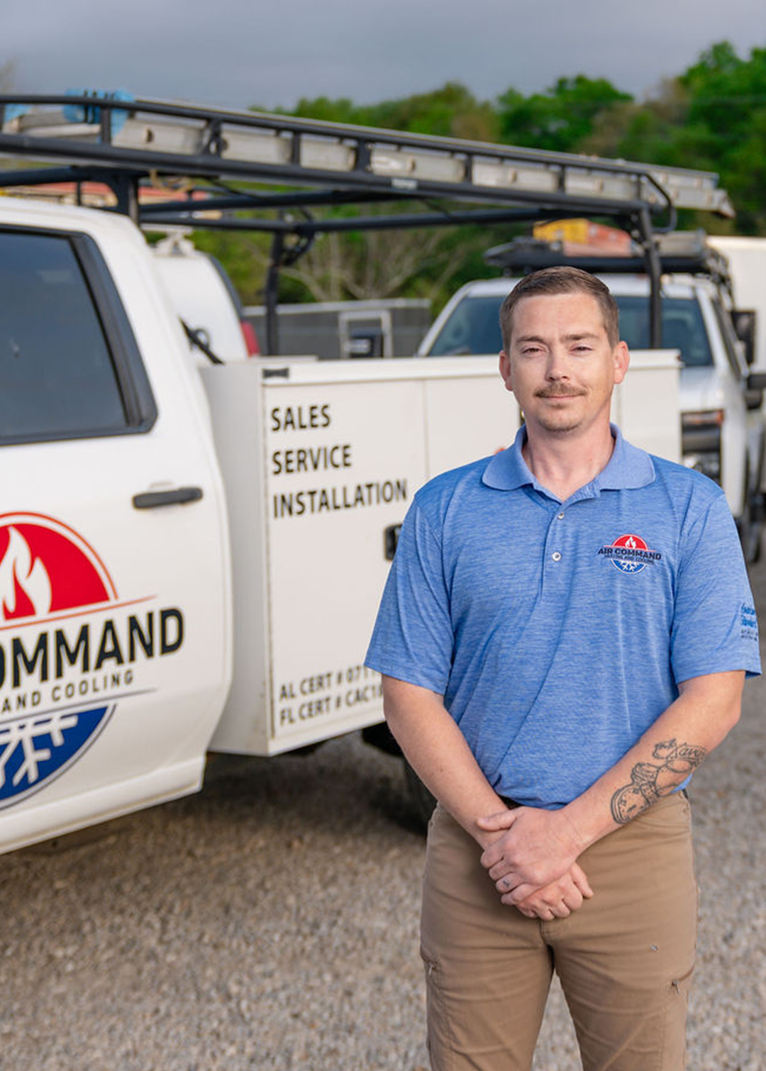 Austin Jordan, Service Technician at Air Command Heating and Cooling, standing in front of company service trucks in Hartford, AL.