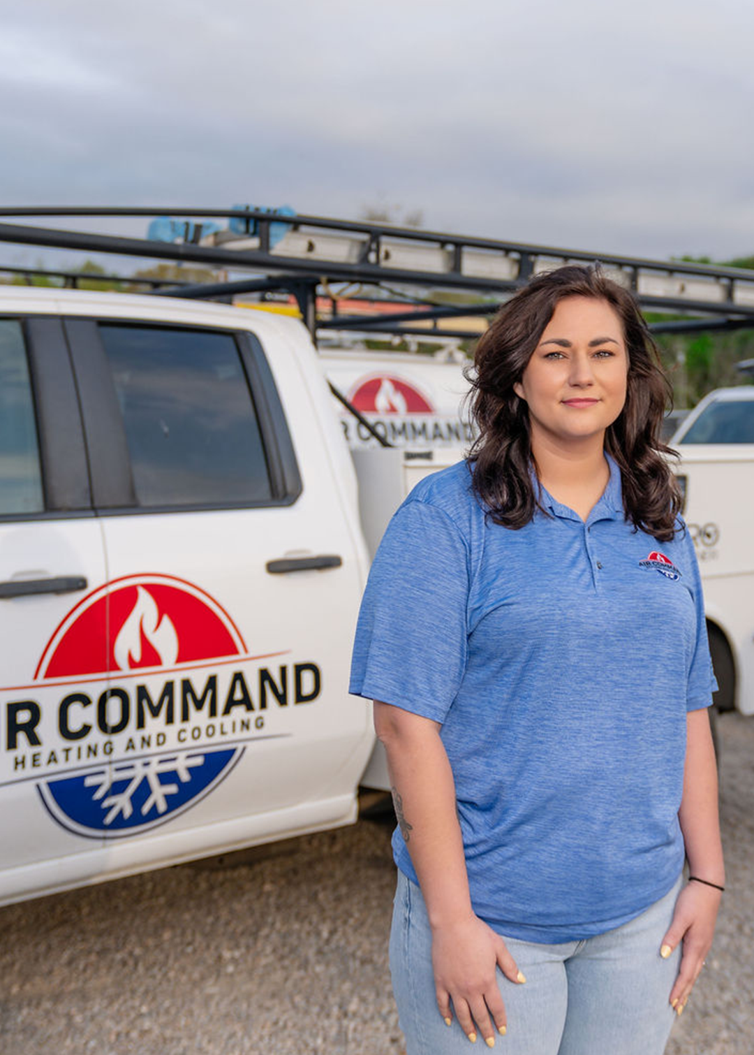 Brianna MacConnell, Office Staff Member at Air Command Heating and Cooling, standing in front of company service trucks in Hartford, AL.