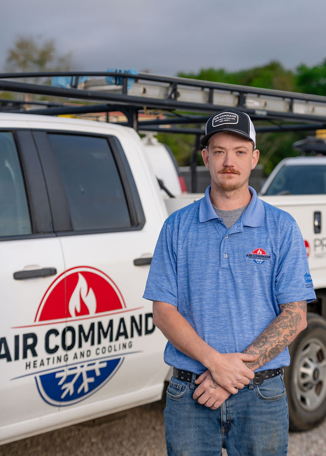 Damon Nelson, Installation Crew Member at Air Command Heating and Cooling, standing in front of company service trucks in Hartford, AL.
