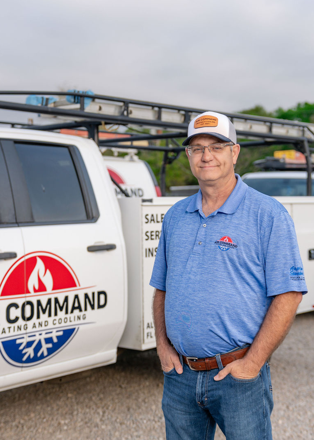 John Commander, Owner of Air Command Heating and Cooling, standing in front of company service trucks in Hartford, AL.