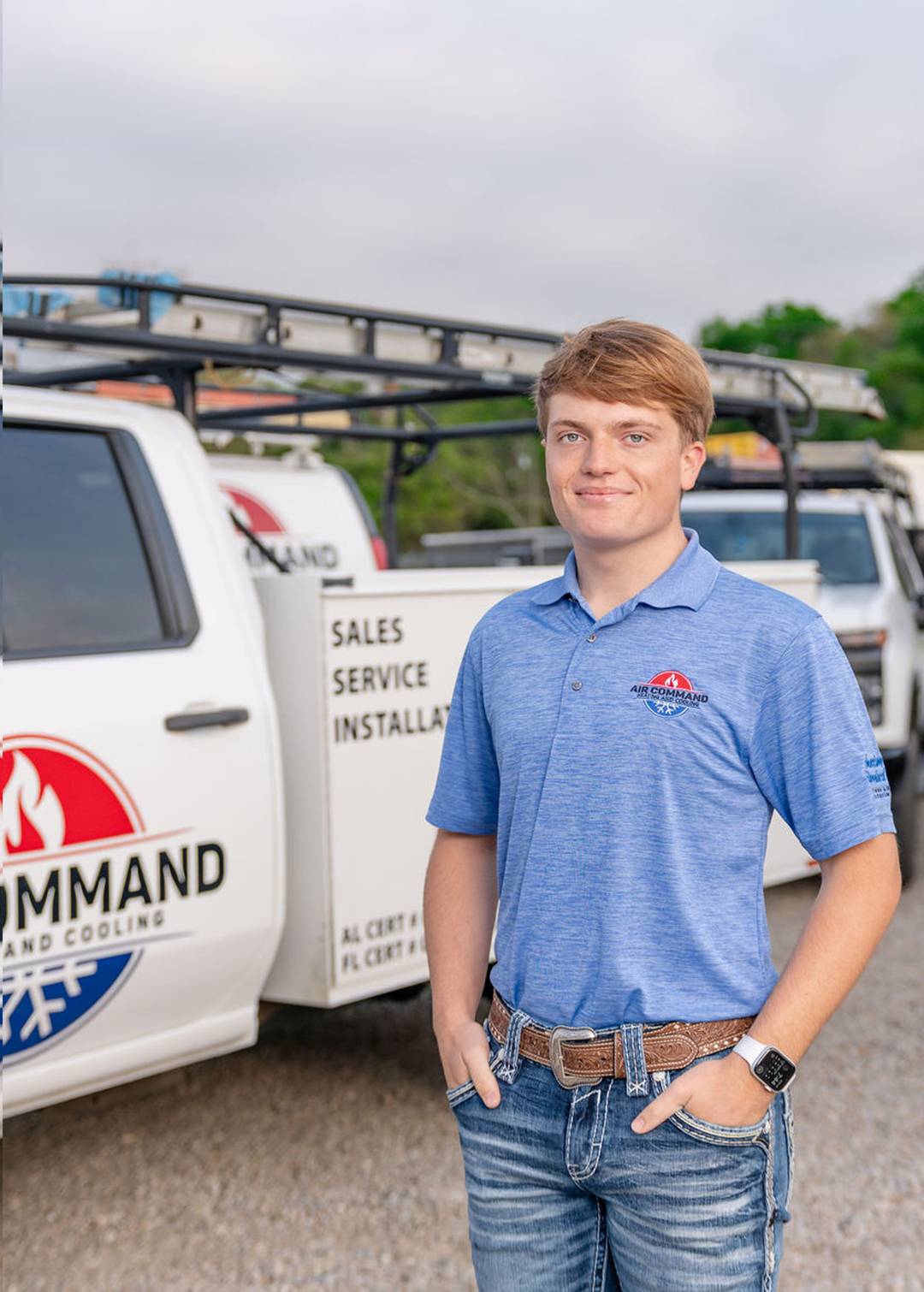 Tyler Commander, Office Staff Member at Air Command Heating and Cooling, standing confidently in front of company service trucks in Hartford, AL.