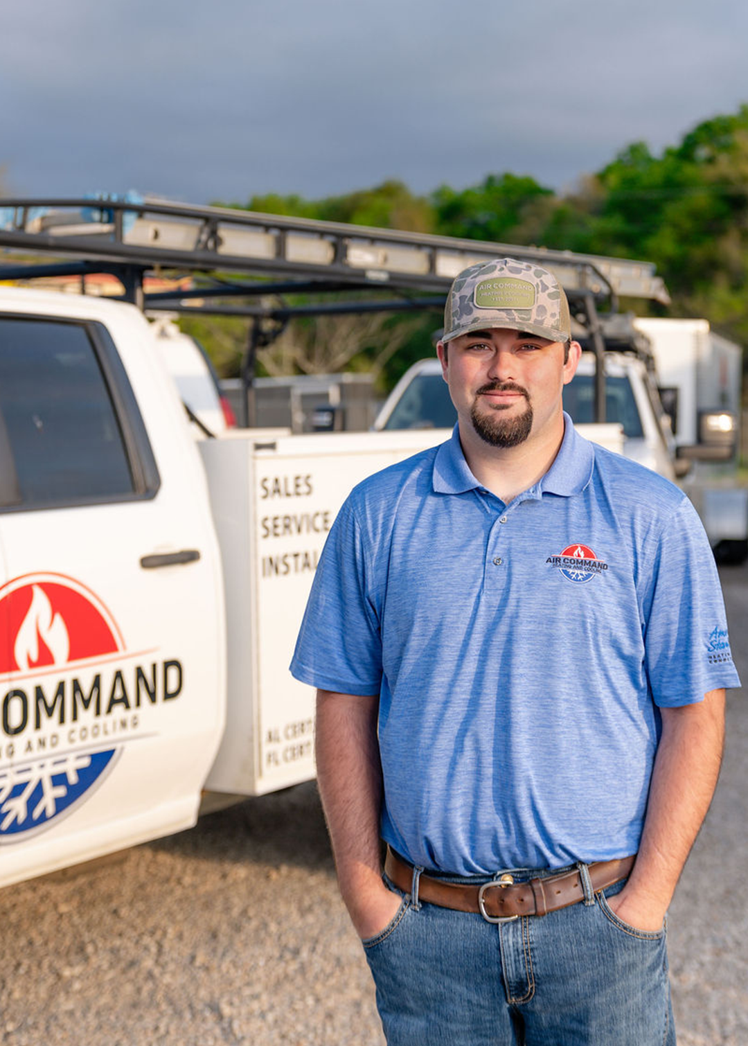 Zae Roy, Installation Crew Member at Air Command Heating and Cooling, standing in front of company service trucks in Hartford, AL.